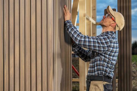 Caucasian Woodwork Worker Building Modern Garden Shed Made From Composite Materials and Wood.