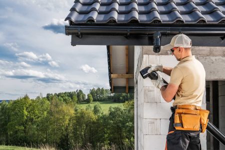 Construction Contractor Roof Worker Installing House Gutters. Construction Site Theme.
